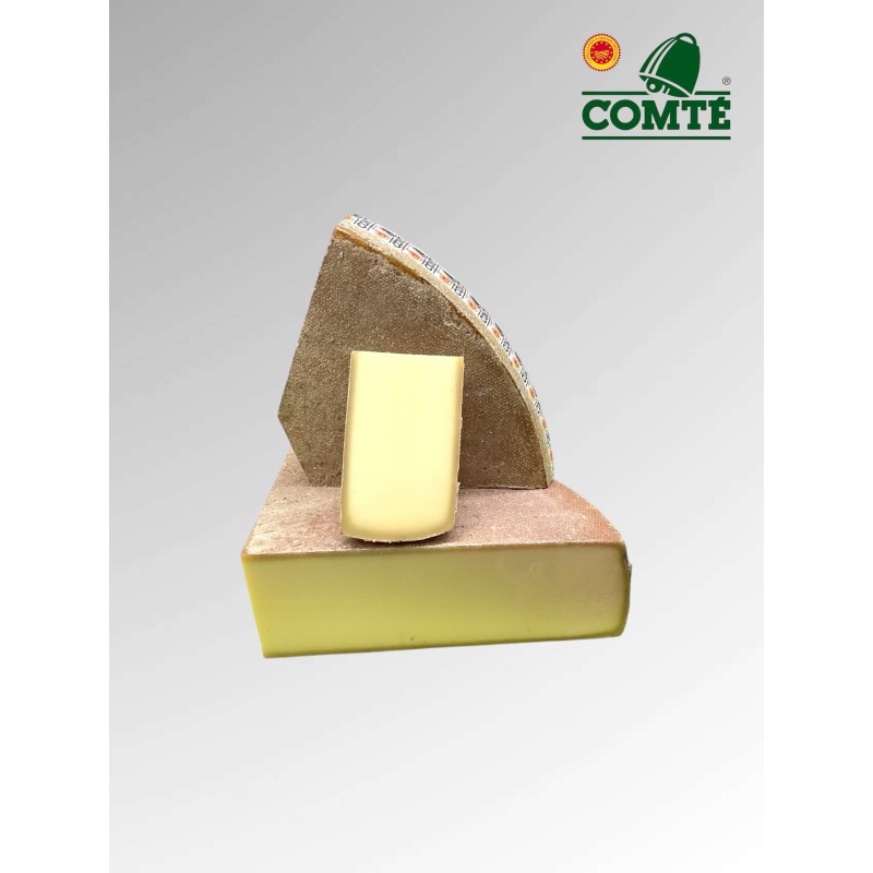 Un beau Comté avec sa croûte brune rugueuse et son intérieur jaune pâle. Sur un fond gris uni.